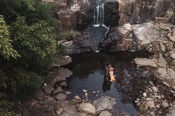 Engaged couple embracing by a waterfall